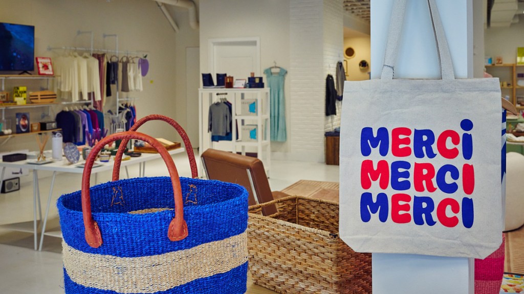 tote bag with writing in French "Merci, Merci, Merci" hanging in store